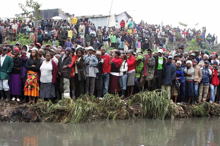 People watch as rescuers work at the scene of a fire at a slum near the industrial area in Nairobi.