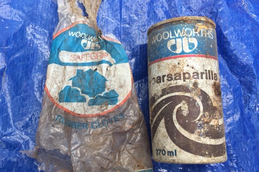 A dirty branded plastic bag and drinking can lie on a blue tarp.