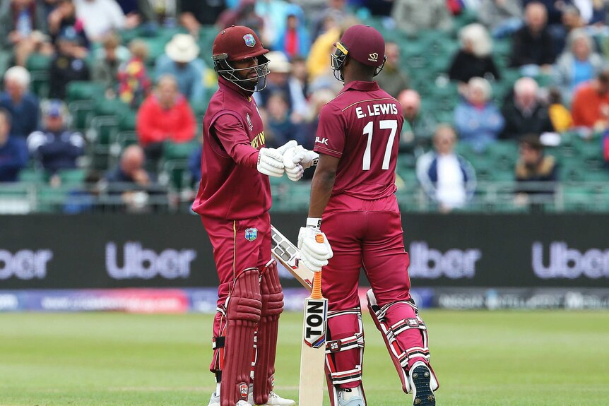 Two batsmen touch gloves mid-pitch after the one on the right reaches his half-century.