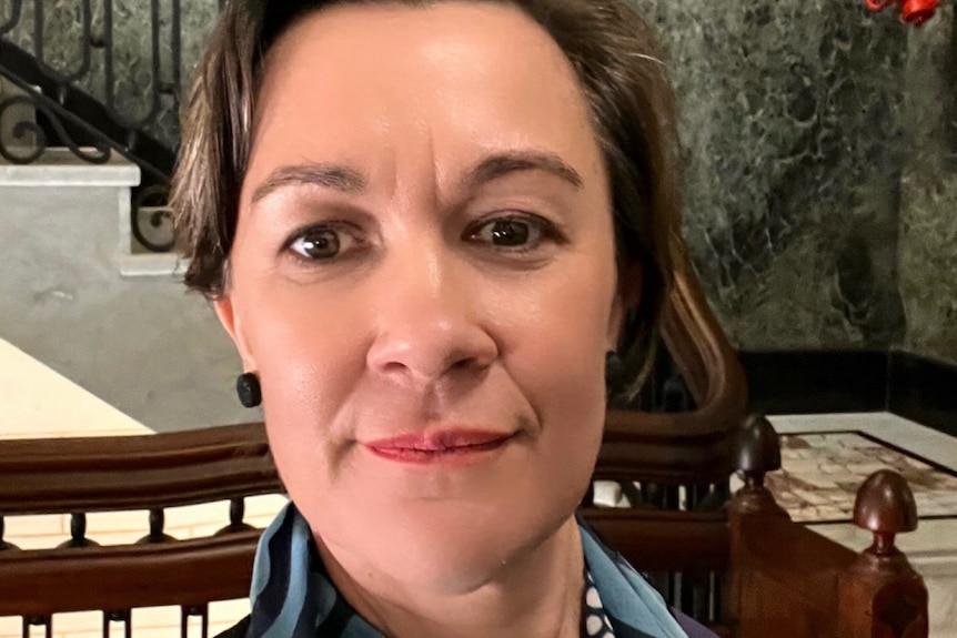 Dark haired woman wearing make up in front of staircase