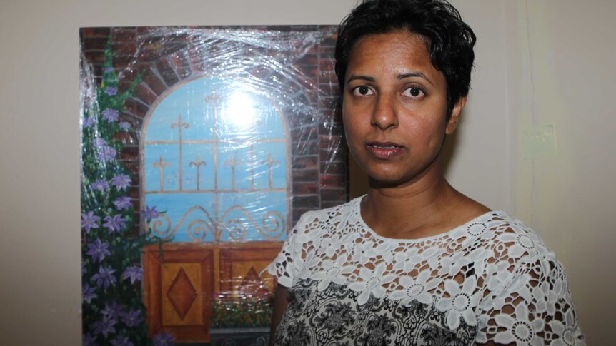 A head and shoulders shot of Chamari Liyanage standing in front of a painting of a window.