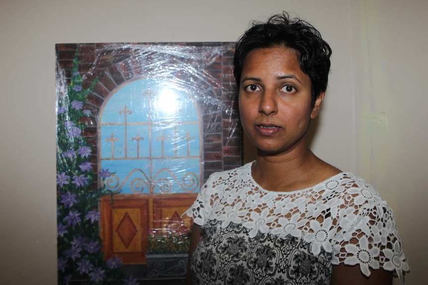 A head and shoulders shot of Chamari Liyanage standing in front of a painting of a window.