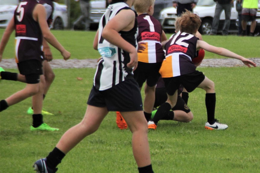 Kids playing Aussie Rules on an oval.