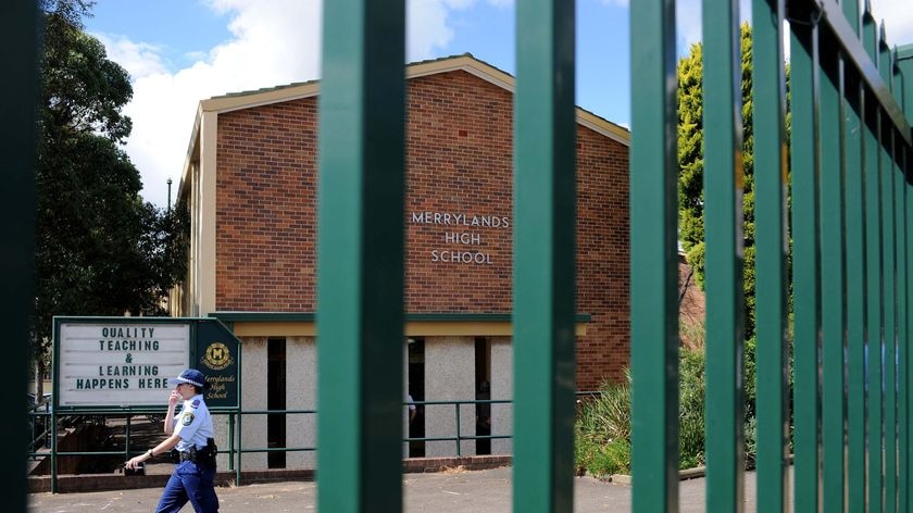 Arrests at gunpoint ... A police officer at Merrylands High School yesterday.