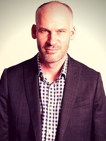 A portrait of a middle-aged man with blue eyes in a jacket.