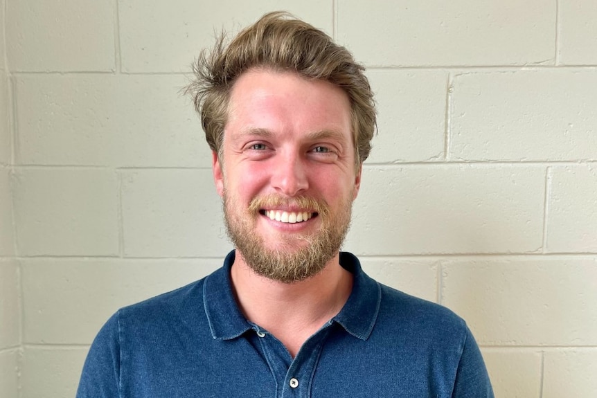 Man in blue polo shirt smiles at camera