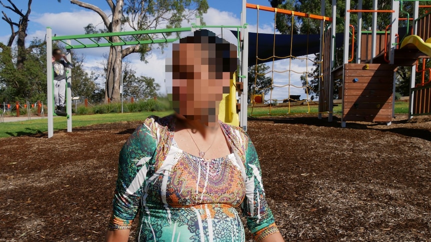 Pregnant woman with pixelated face in playground.