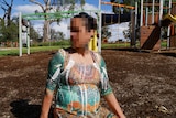 Pregnant woman with pixelated face in playground.