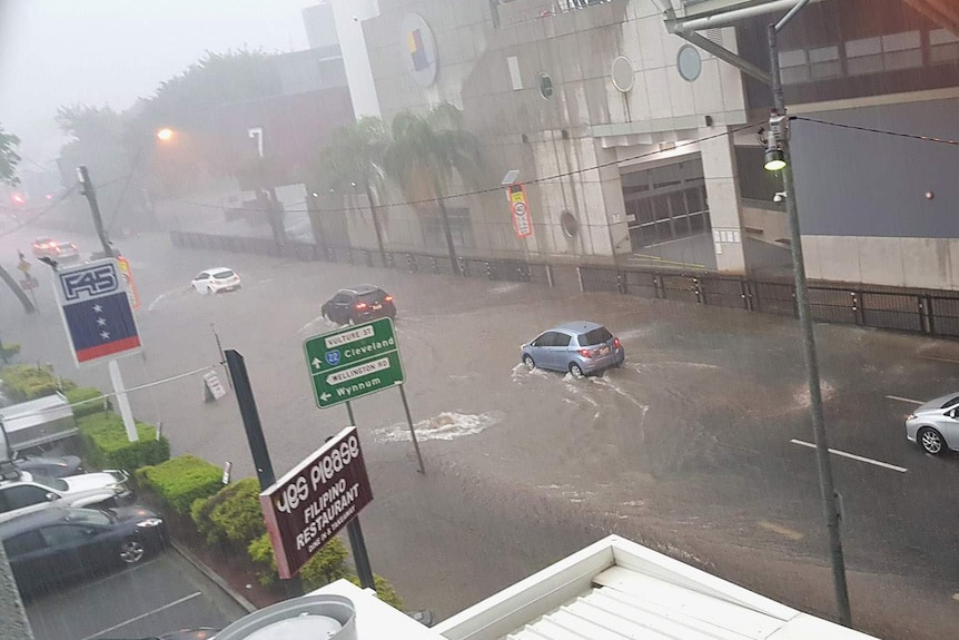 Cars driving into a flooded section of road outside the Gabba
