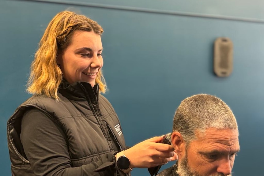 a woman shave a mans head. 