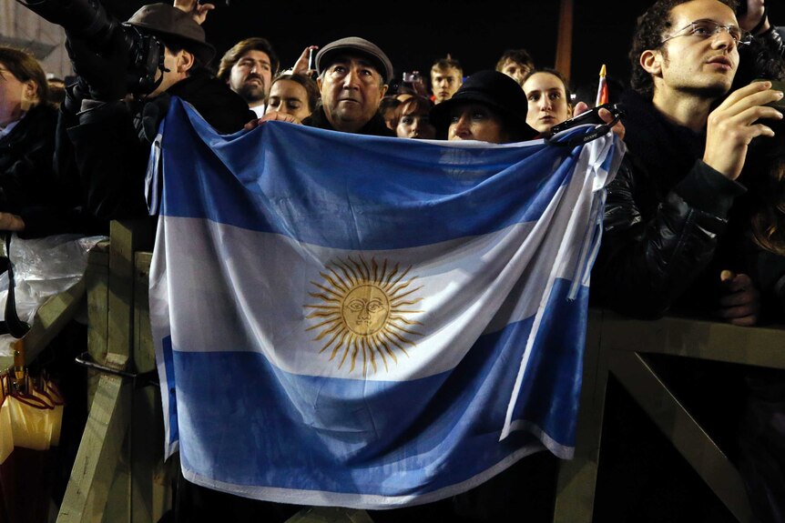 Faithful cheer holding Argentina's flag as Pope Francis appears on the balcony of St Peter's Basilica at the Vatican.