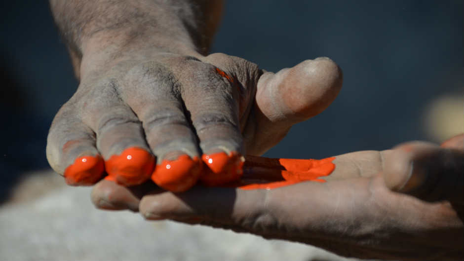 An Aboriginal dancer rubs red paint between his fingers