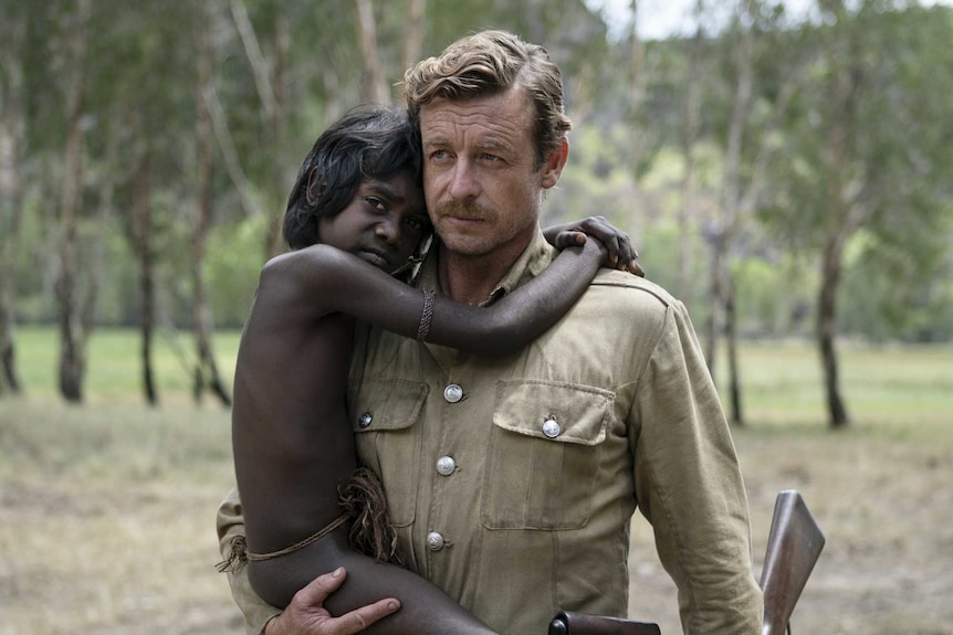 A still from the film High Ground of a white soldier (Simon Baker) holding a young Aboriginal boy (Guruwuk Mununggurr) in 1930s