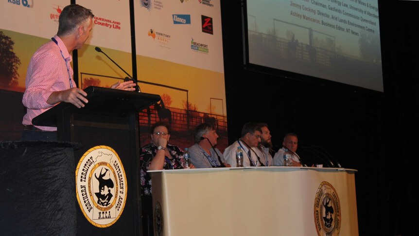 A picture of people sitting on a panel at a conference