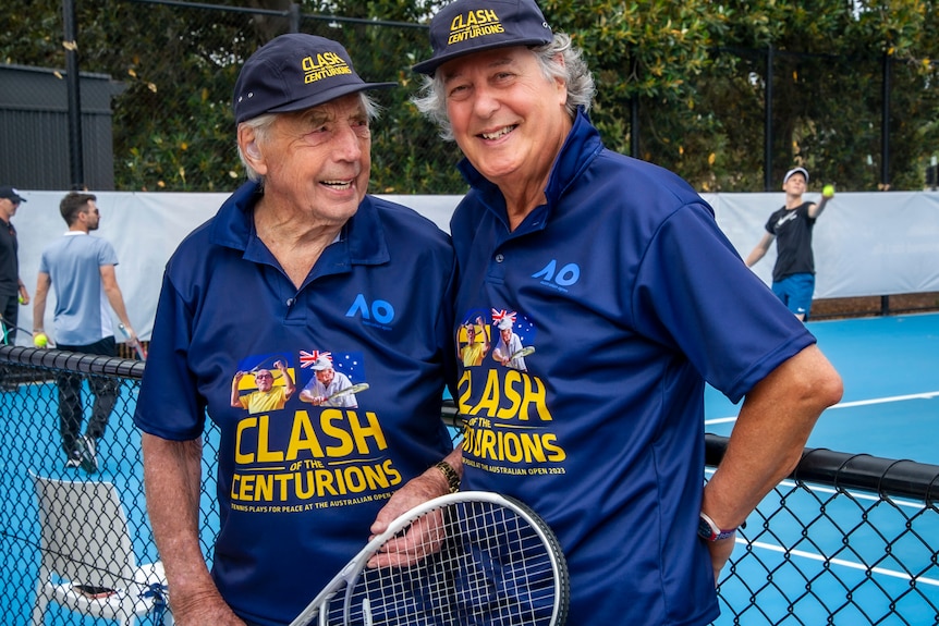 Two men wearing blue at a tennis court.