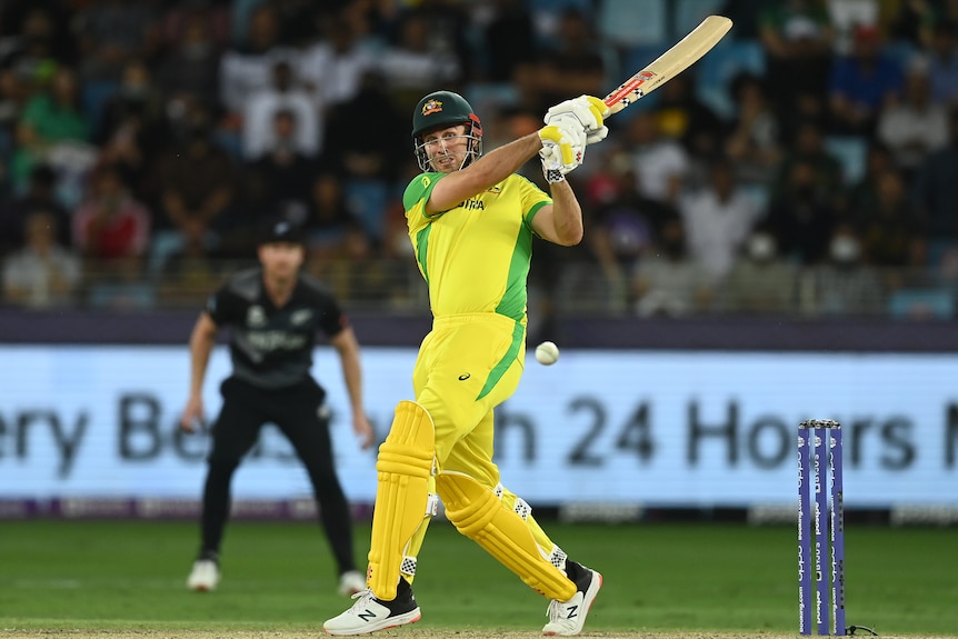 Cricket batter in yellow hits a pull shot.