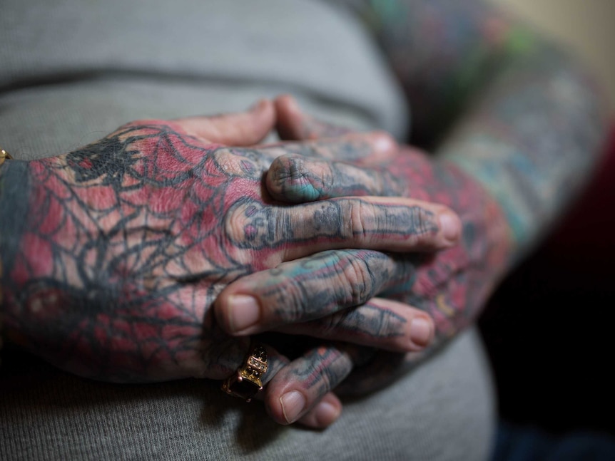 Close-up of tattoo-covered hands with amputated finger.