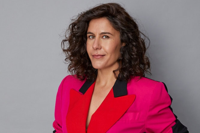 Broadcaster Jan Fran wearing bright pink and red blazer with black skirt.