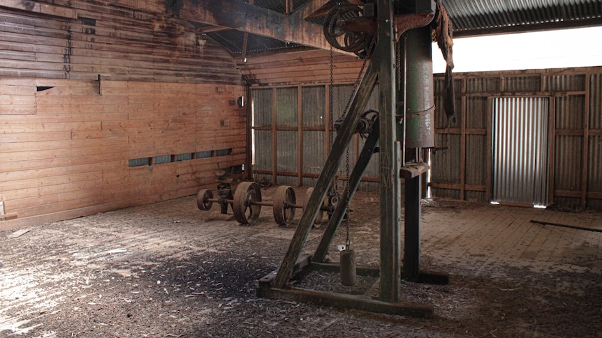 A dilapidated room with old and rusty machinery and wooden walls.
