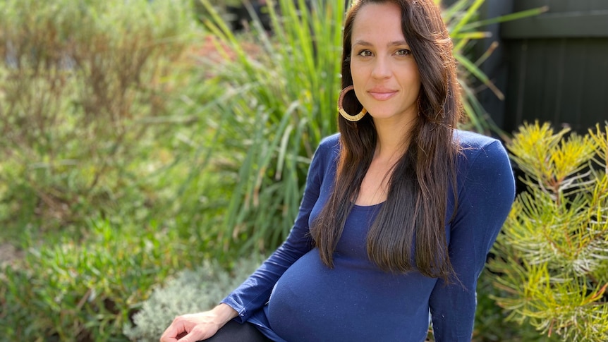 A pregnant woman sitting down for a story on the safety of COVID vaccine during pregnancy.