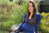 A pregnant woman sitting down for a story on the safety of COVID vaccine during pregnancy.