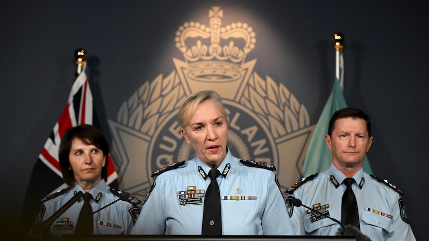 katarina behind a lectern flanked with police at a press conference