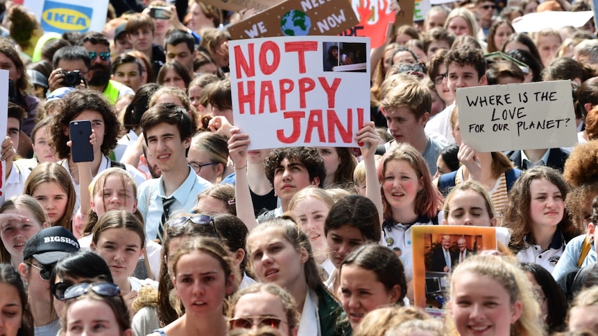 In a large crowd of protester, someone holds a sign that reads "Not happy Jan".