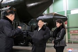 Kim Jong Un stands with his daughter in front of a transport erector. 
