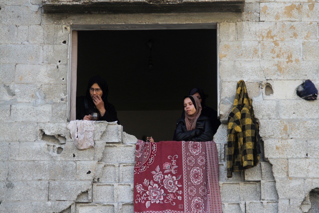 Two women peering our an opening in a building