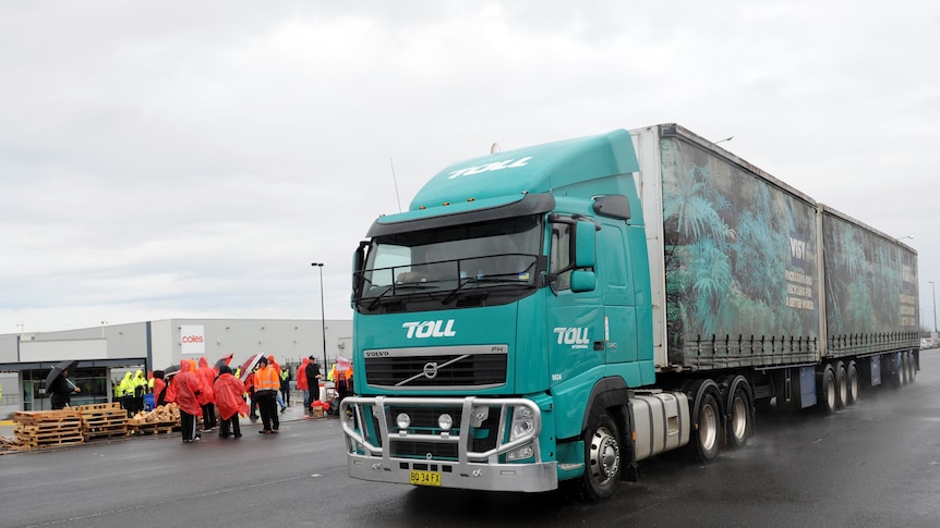 A truck belonging to Toll Group drives on a road on an overcast day
