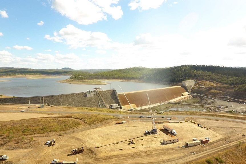 Drone photo of construction vehicles and workers at the spillway of a dam.