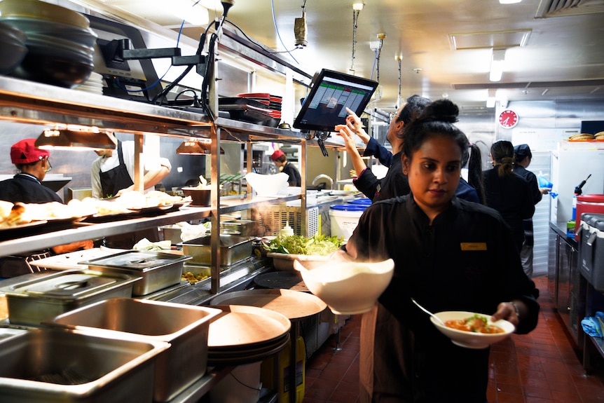 A waitress takes out plates of food from the kitchen at Darwin restaurant, Hanuman.  