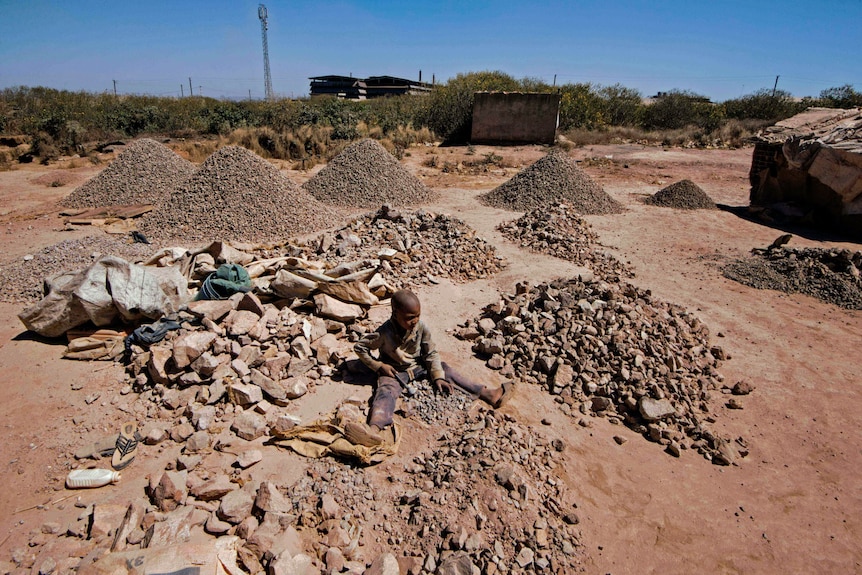 A boy sitting among mounds of rock