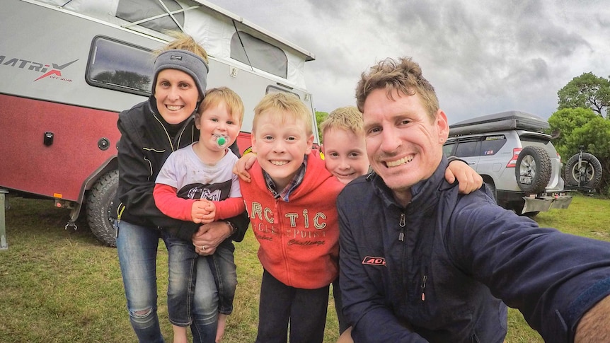 Ryan and Amy Murphy pose with their three young boys in front of their camper and four-wheel-drive