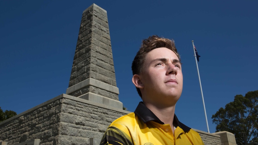 A young man sits near a war memorial