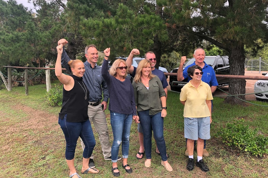 Group of residents stand together smiling with their fists raised in the air.