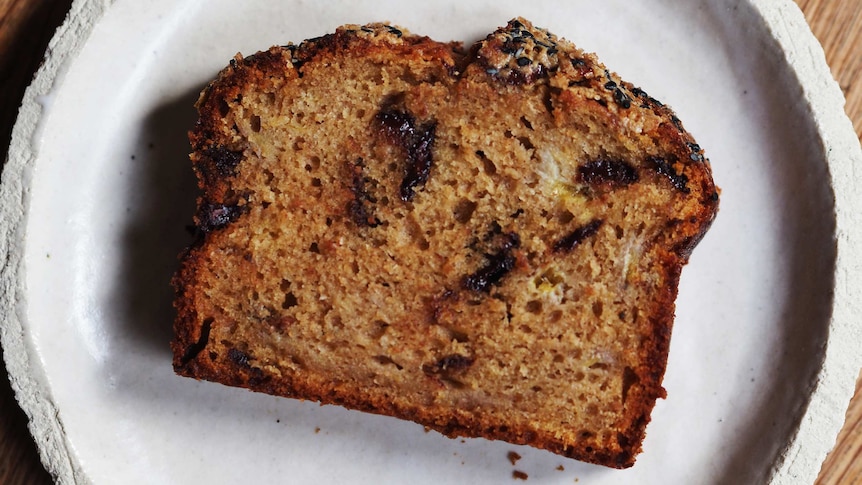 A slice of banana bread on a plate with chocolate, spices and a crunch tahini top: an easy banana bread recipe.