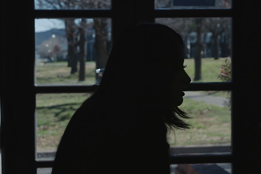 A silhouette of a woman or girl against a window.
