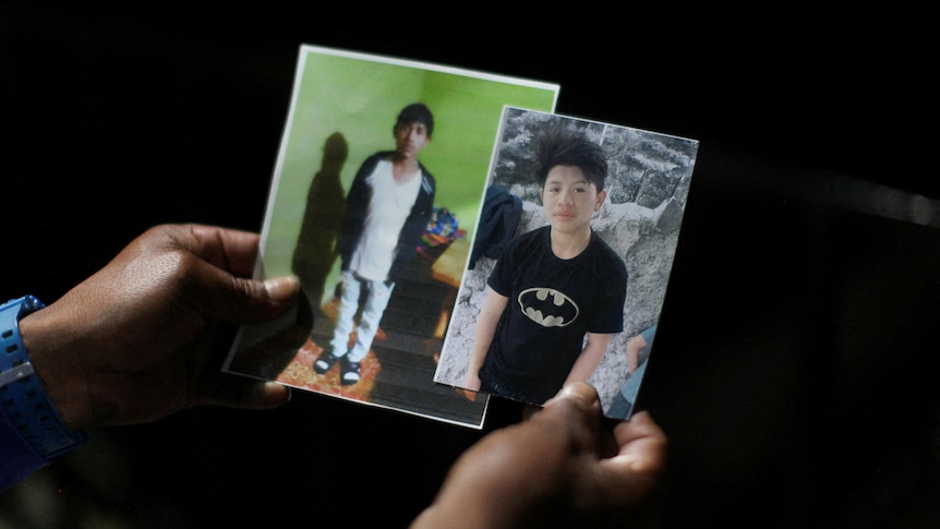 A woman holds photos of 13 year-old Melvin Guachiac and 14-year-old Wilmer Tulul.