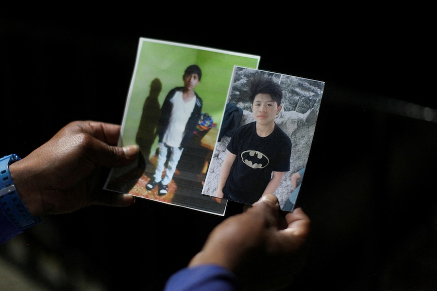 A woman holds photos of 13 year-old Melvin Guachiac and 14-year-old Wilmer Tulul.