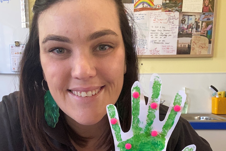 Emma Fenton holding up a paper craft to teach the children.