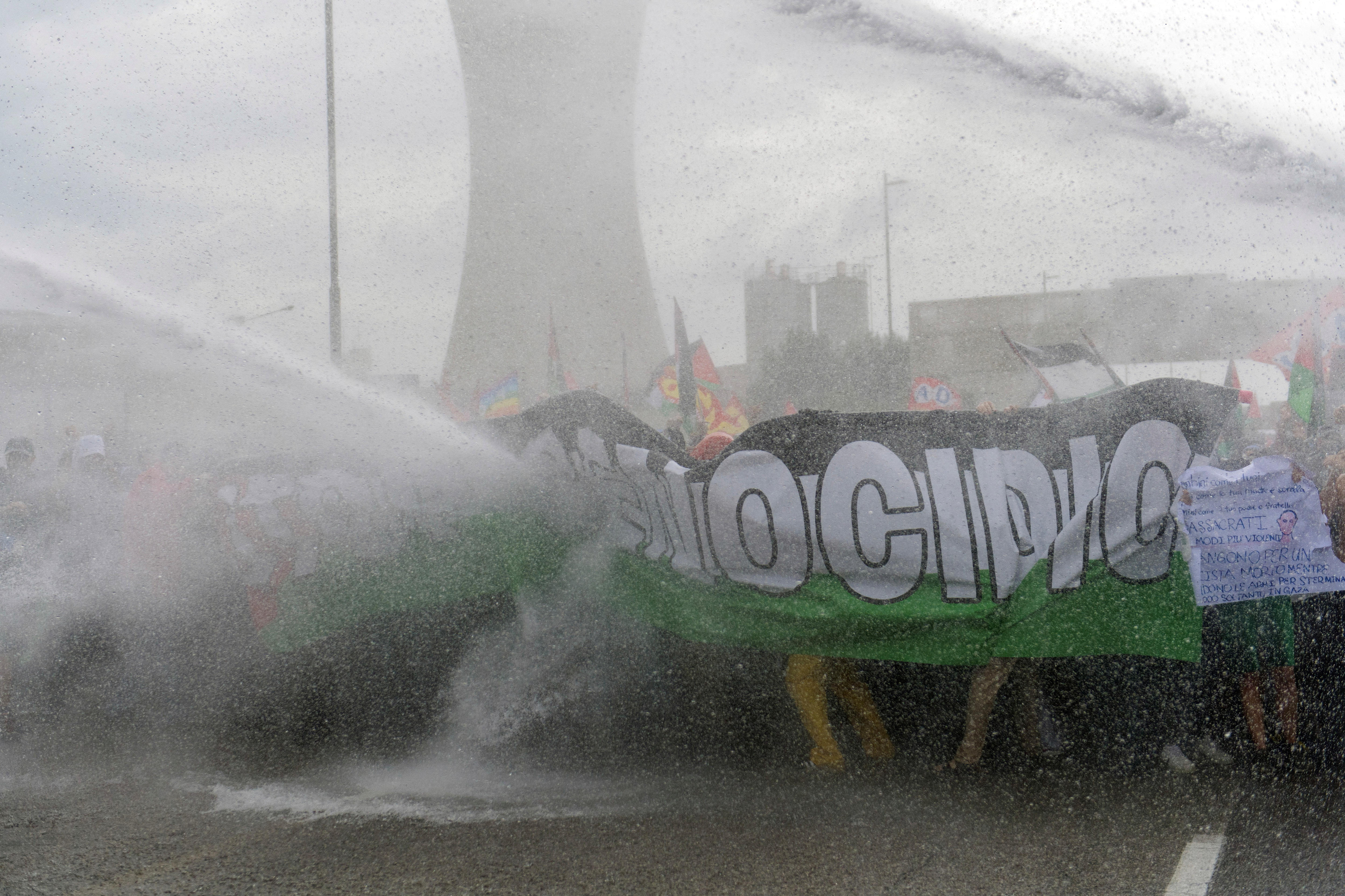 A Palestinian anti-genocide banner and protesters being hit by water cannons.