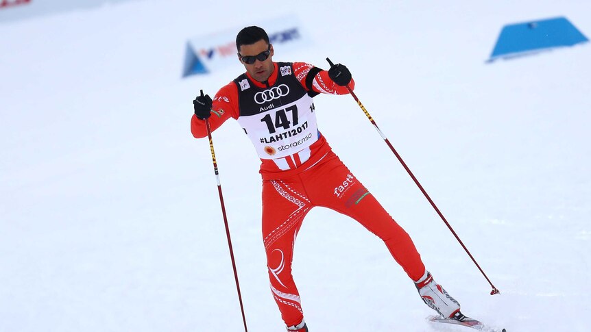 Pita Taufatofua skiing whilst wearing a red and white ski suit.