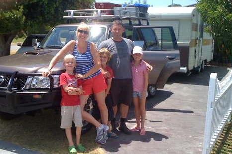 Mandy Farabegoli stands with her family in front of their car.