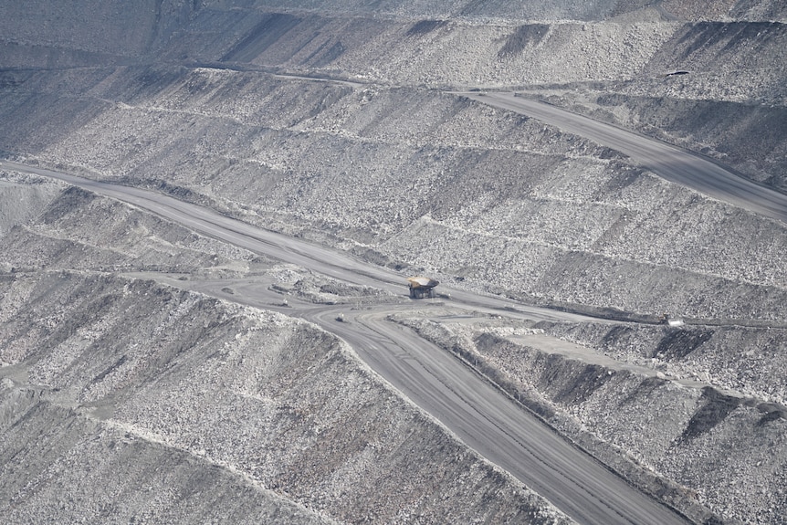 A coal truck drives along an open cut coal mine.