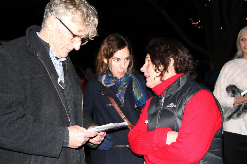 David Astle reads a program while Annette Baker talks to Holly Throsby.