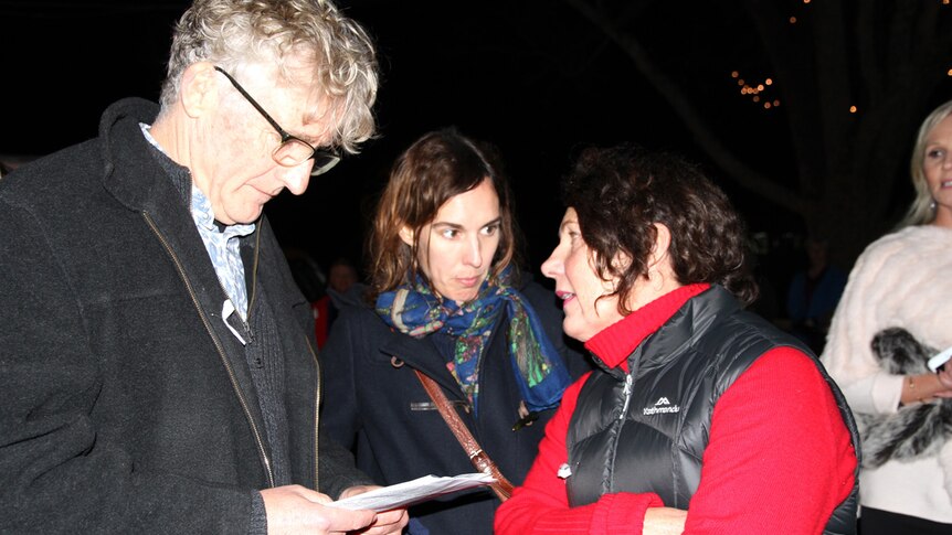 David Astle reads a program while Annette Baker talks to Holly Throsby