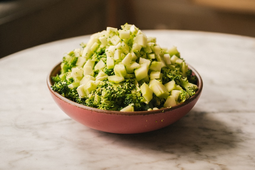 Bowl of chopped broccoli, including florets and steam. Chopped into one to two centimetre pieces, to go into an easy pasta.