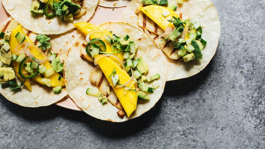 Soft tacos on a plate topped with haloumi, mango and cucumber avocado salsa for a quick summer recipe.