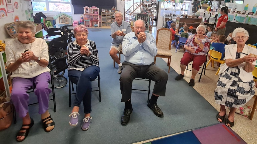 Seniors sitting in a child care centre holding baby chicks